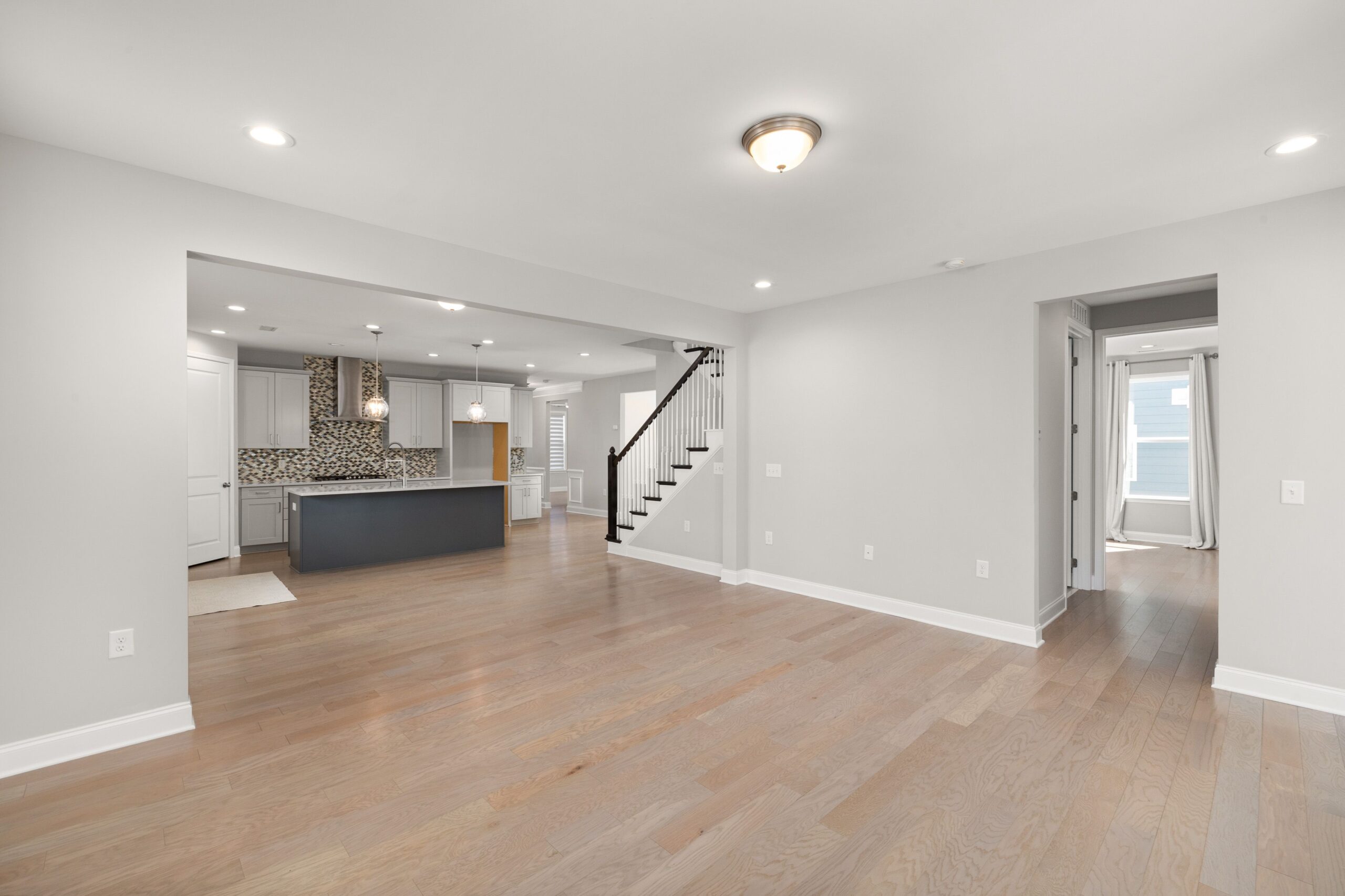 Spacious open-concept living room with hardwood floors and modern kitchen design.