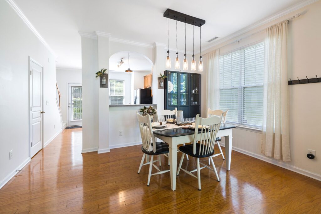 Bright and spacious dining room with stylish wooden floors and elegant hanging lights.
